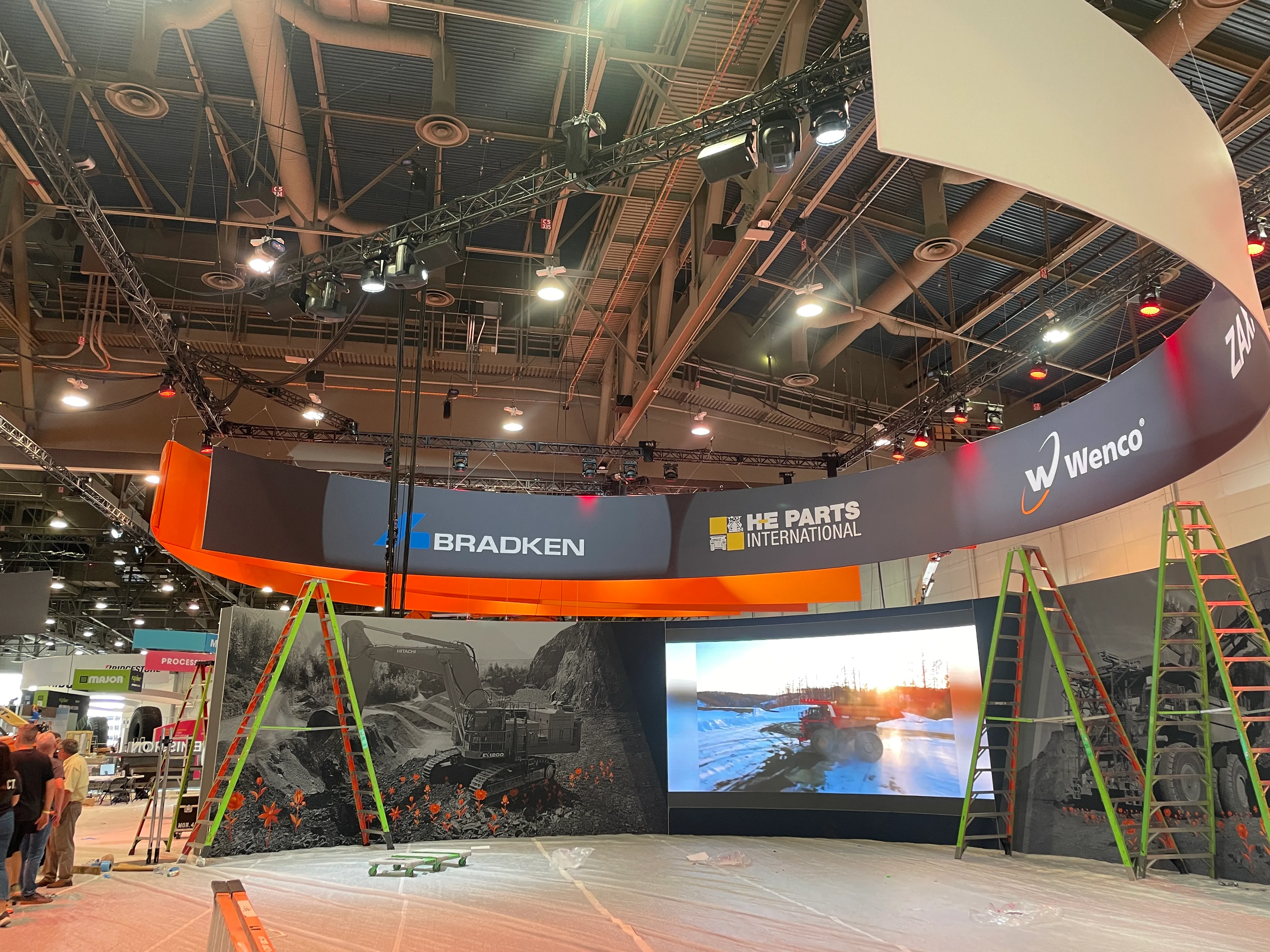 Curved LED backdrop and live band setup inside the Hitachi MINExpo trade show booth